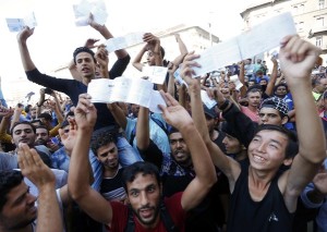Migrants wave their train tickets outside the main Eastern Railway station in Budapest