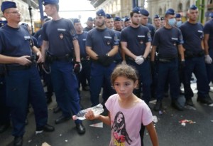A girl walks past a line of Hungarian police at the main Eastern Railway station in Budapest